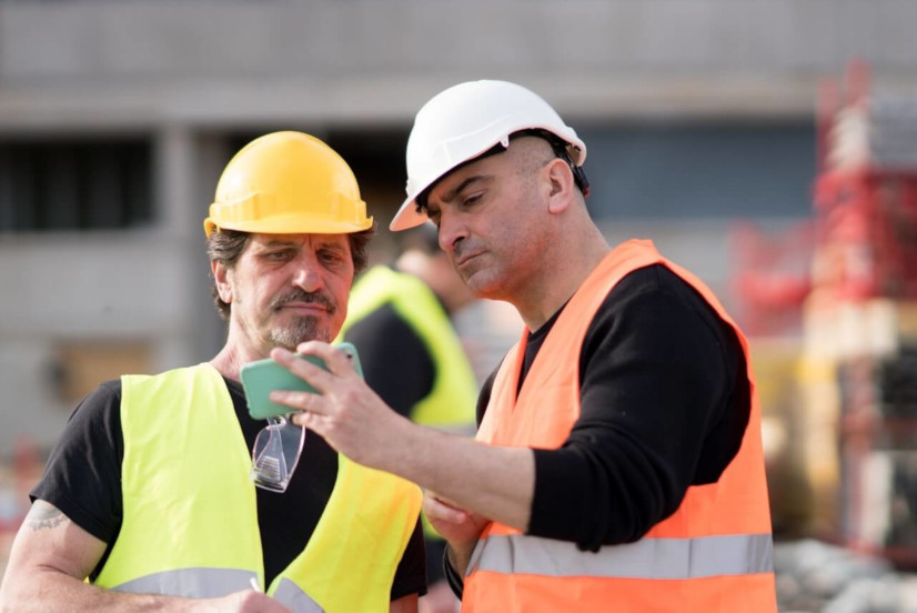 Two construction workers with one smartphone