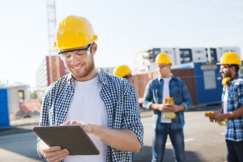smiling site manager using tablet on construction site