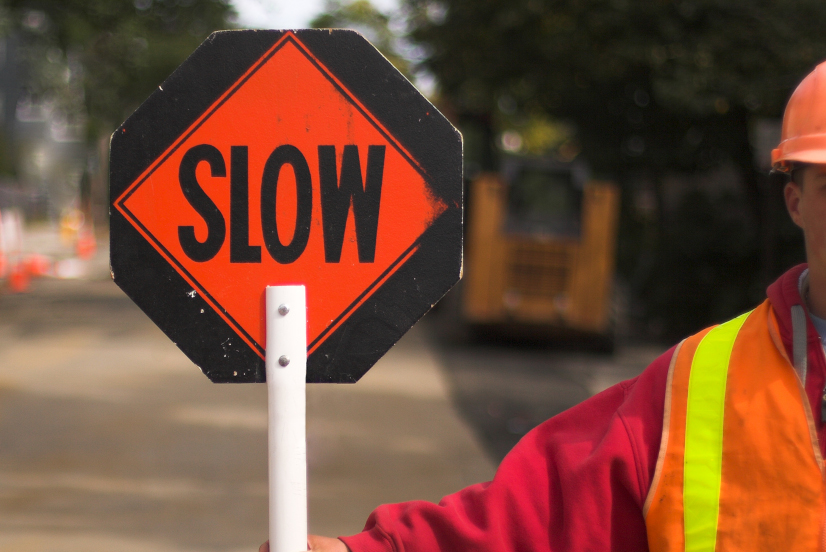Verkehrspolizist lenkt den Verkehr und hält das Schild "Slow"