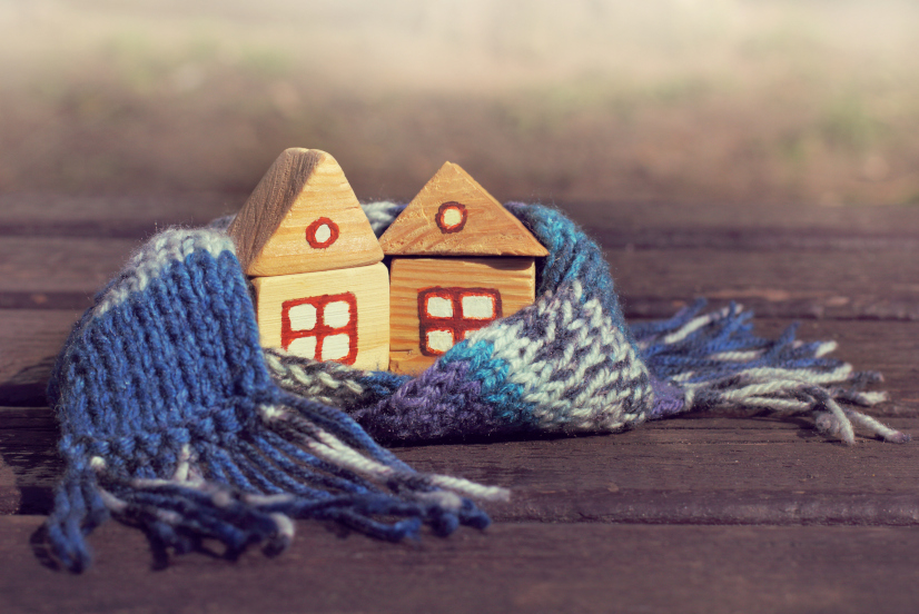 Symboldbild für Dämmung: Kleine Holzhäuser mit blauem Schal