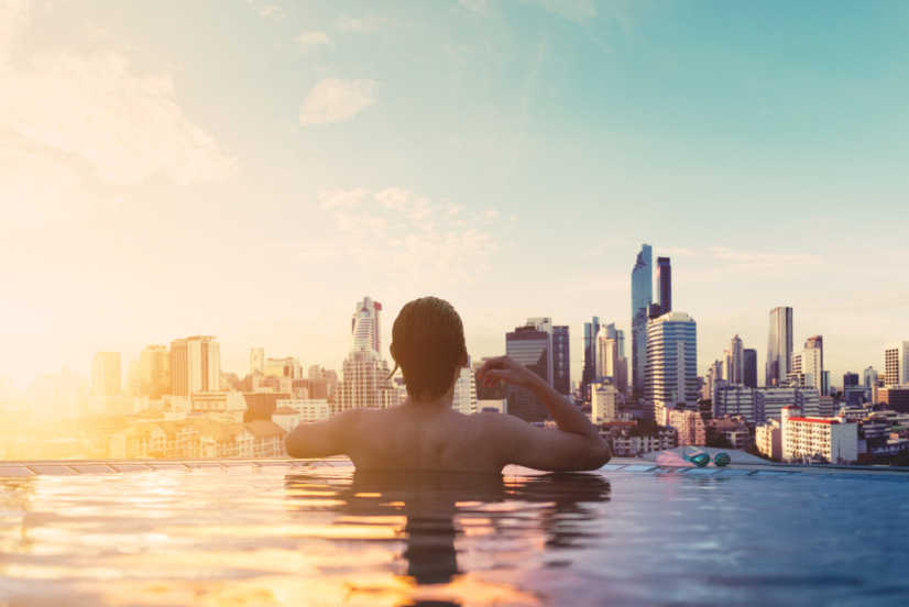 a man relax in swimming pool in sunrise, on rooftop in the city