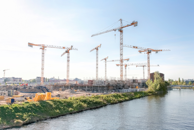 Eine große Baustelle mit vielen Kränen auf einem Fluss, an einem sonnigen Tag - Berlin 2018