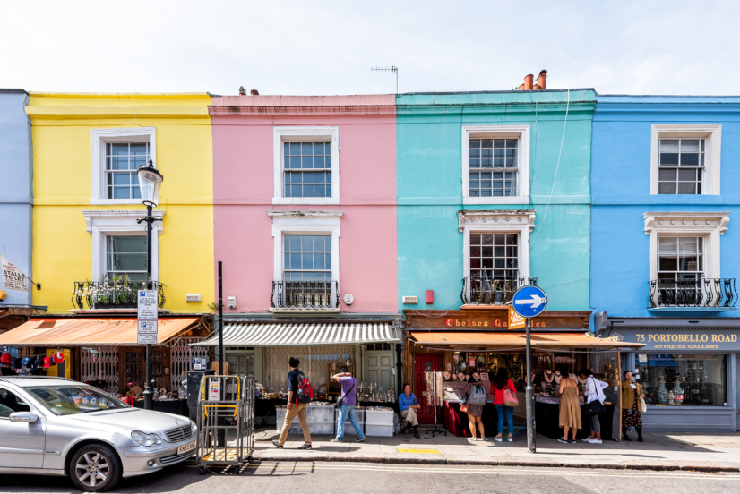 London, UK - June 24, 2018: Neighborhood district of Notting Hill, street, colorful multicolored famous style flats architecture facade, road, people shopping in iconic center, Portobello