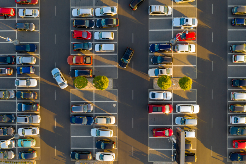 Top down view from drone on mall parking with many cars.