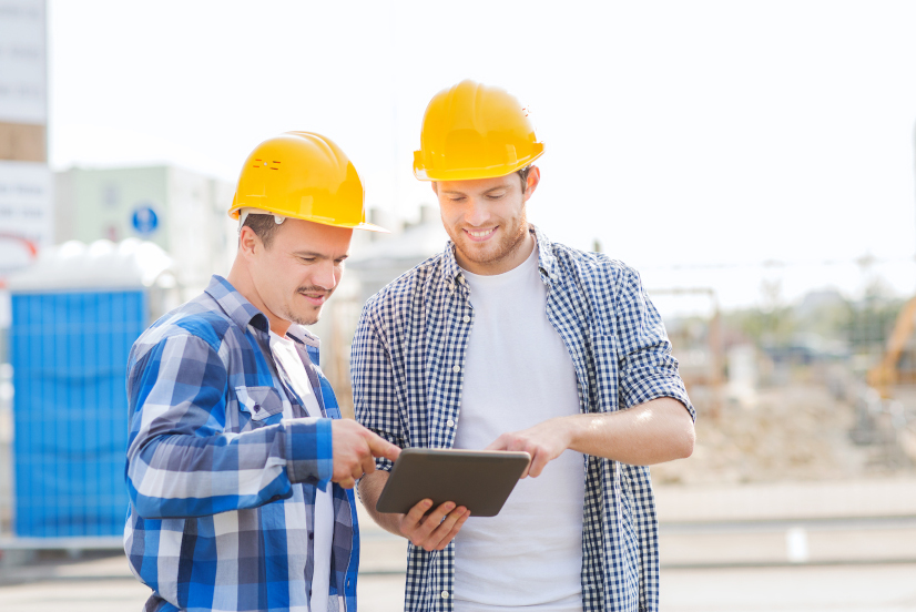 Two construction professionals completing a practical completion checklist on a tablet.