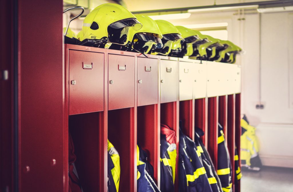 image of a set of clothing lockers at a fire station. the lockers contain fire protective equipment and safety helmets